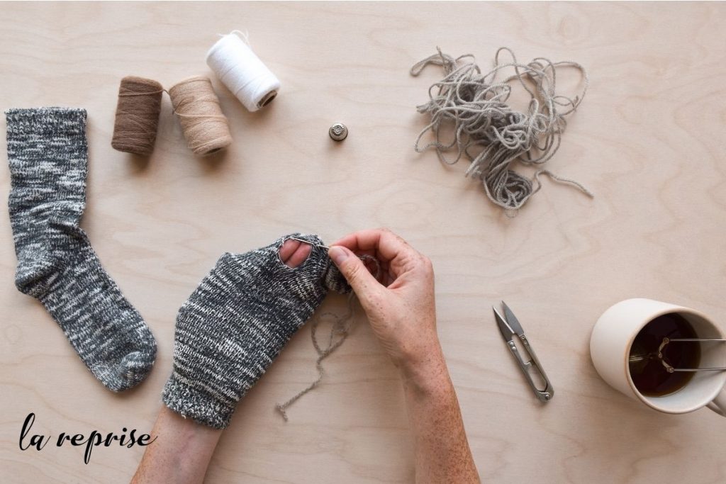 Reprise artisanale d'une chaussette en laine avec fil et aiguille.
